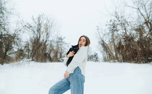 Stylová Žena Bílém Svetru Džínách Stojící Ulici Sněhu Černou Kočkou — Stock fotografie