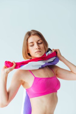 Pembe spor kıyafetli güzel bir kadın beyaz arka planda kameraya poz veriyor..