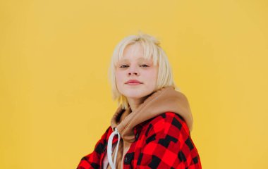 Sarı arka planda izole edilmiş sarı saçlı tatlı bir kızın yakın portresi. Ciddi bir yüzle kameraya bakıyor..