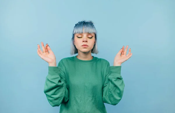 Menina Séria Uma Camisola Verde Fica Fundo Azul Medita Com — Fotografia de Stock