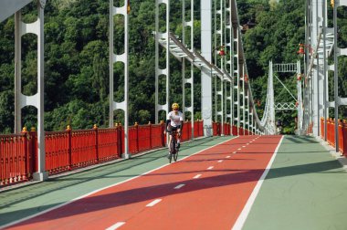 Erkek sporcu, güneşli bir yaz gününde köprüde bisiklet sürüyor..