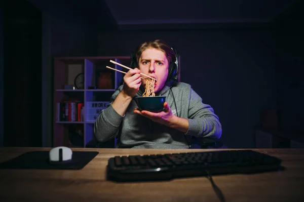 Hungry Young Male Gamer Headset Sits Night Computer While Playing — стоковое фото