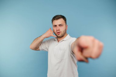 Tüylü adam çağrının jestini gösteriyor ve mavi arka planda parmağını kameraya doğrultuyor..