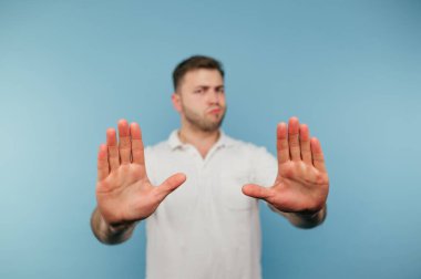 Beyaz tişörtlü tatminsiz adam avuçlarını kameraya gösteriyor..