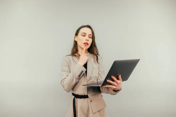 Pensive Business Woman Laptop Her Hands Stands Beige Background Looks — Stockfoto