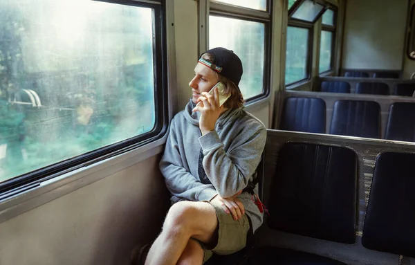 一个穿着休闲装的积极向上的男人坐在窗边 面带微笑地看着窗外 在电话里交谈 — 图库照片