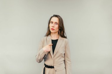 Şaşırmış bej takım elbiseli kadın ofis çalışanı kameraya bakar ve bej arka planda izole edilmiş şok olmuş bir yüzle kendini gösterir..