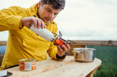 Adam dağlarda yemek pişiriyor, benzin masasında, kullan-at telefon kullanıyor..