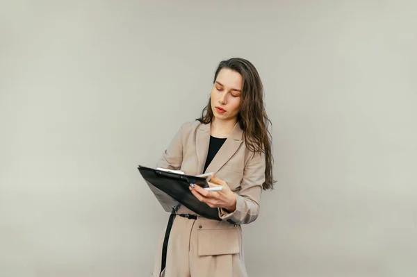 Business Woman Jacket Stands Beige Background Writes Pen Tablet Serious — Stockfoto