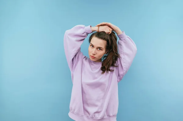 Beautiful Girl Purple Sweatshirt Stands Blue Background Poses Camera Serious — Fotografia de Stock