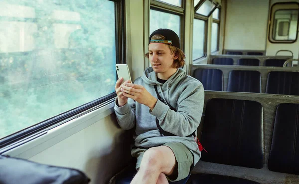 Позитивний Хлопець Смартфоном Руках Сидить Потязі Біля Вікна Під Час — стокове фото