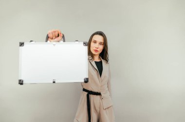 Elinde metal bir çanta olan iş kadını bej bir arka planda izole edilmiş..