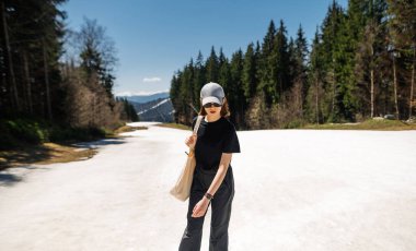 Şık bir bayan yürüyüşçü dağlarda yürürken karın üzerinde duran bir dağ beldesinde yürüyor..