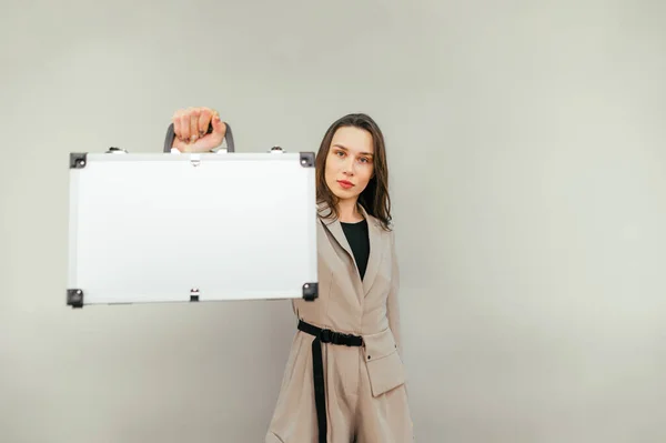 Business woman with a metal case in her hands isolated on a beige background.
