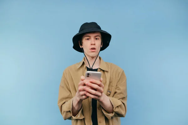Portrait Surprised Young Man Panama Shirt Blue Background Looks Smartphone — Foto de Stock