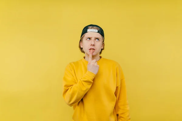 Handsome Guy Cap Yellow Sweatshirt Stands Yellow Background Looks Pensive — Foto Stock