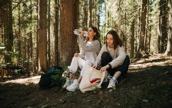 Two Beautiful Women Tourists Sitting Woods Resting Hike Drinking Water — Stok fotoğraf