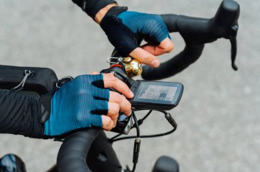 Bisiklet gidonunda bisiklet bilgisayarı olan profesyonel bir bisikletçinin elleri..