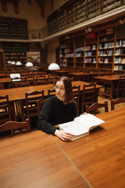 Приваблива Жінка Сидить Столом Публічній Бібліотеці Університету Книгою Руках Дивиться — стокове фото