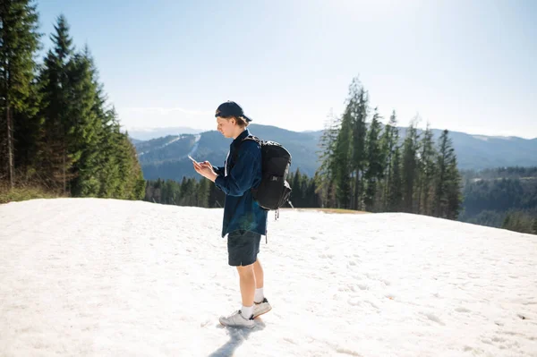 여름철에 을등에 산속을 남자가 산속의 눈덮인 산비탈에서 산속의 스마트폰을 — 스톡 사진