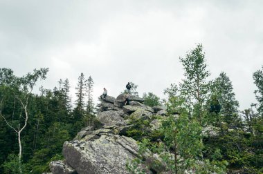Group of tourists are sitting in the mountains on a rock. Active rest in the mountains, hiking