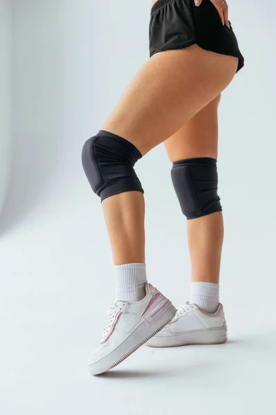 Legs of a woman dancer in knee pads on a white background. Close vertical photo.