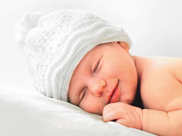 Bebê recém-nascido sorridente em chapéu branco — Fotografia de Stock