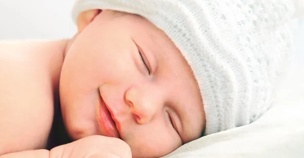 Bambino appena nato sorridente in cappello bianco Foto Stock