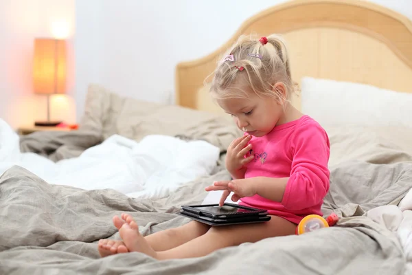 Toddler girl playing with tablet pc in bed — Stock Photo, Image