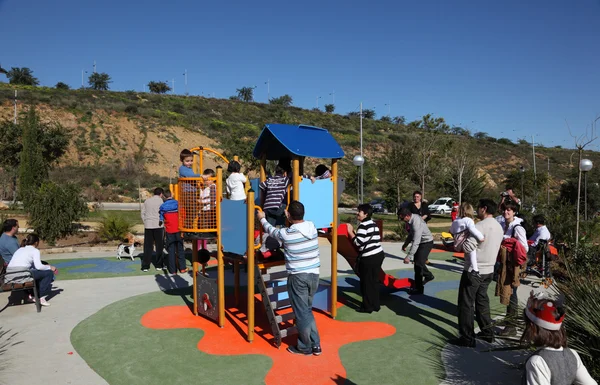 Pais com seus filhos em um playground lotado. Estepona, Andaluzia, Espanha — Fotografia de Stock