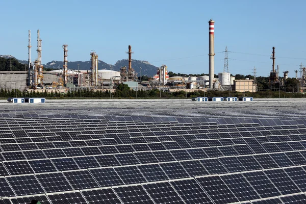 Central solar con una refinería de petróleo en el fondo — Foto de Stock