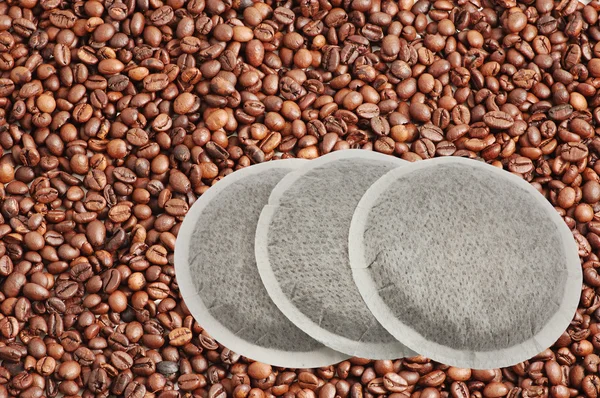 Kaffeepads isoliert über Kaffeebohnen — Stockfoto