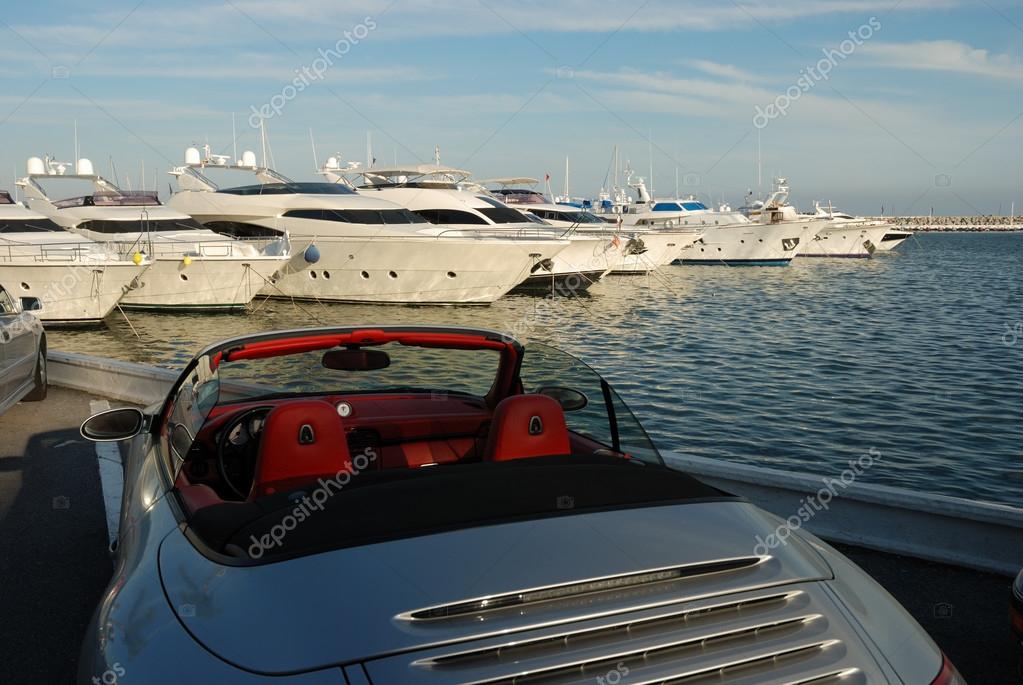 Luxury sports car and yachts in the harbor of Marbella, Spain Stock