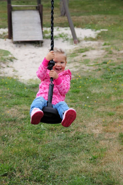 Happy girl on a swing in the city park — Stock Photo, Image