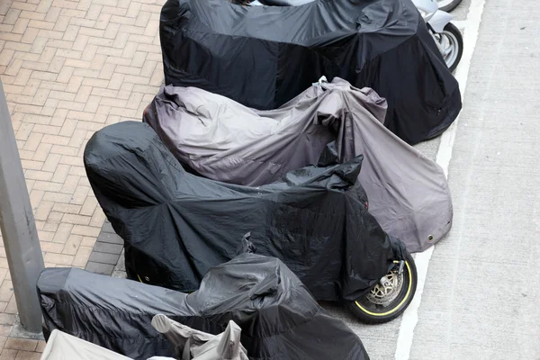 Motos couvertes garées dans la rue — Photo