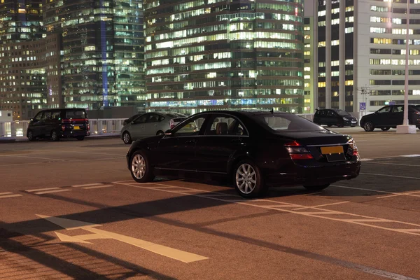 Carros em um estacionamento na cidade à noite — Fotografia de Stock