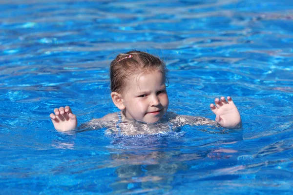 Happy little girl swims in the resort pool — Stock Photo, Image