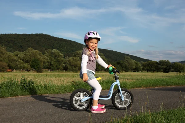 Happy four year old girl on a training bike — Stock Photo, Image