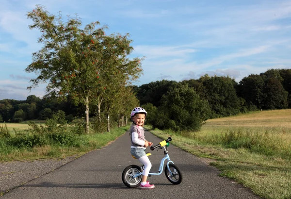 Gelukkig meisje op haar opleiding fiets buitenshuis — Stockfoto