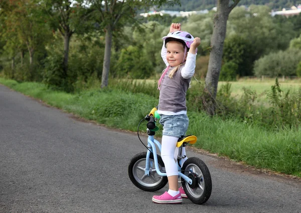 Feliz niña en bicicleta de entrenamiento haciendo gestos de su victoria —  Fotos de Stock