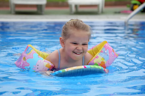 Little girl swimming with board and water wings in pool — Stock Photo, Image