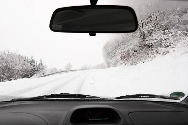 Driving a car on a snowy country road in winter