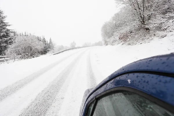 Carro em uma estrada de país nevado no inverno — Fotografia de Stock