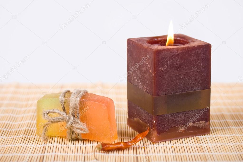 Soap and candle on a bamboo background.