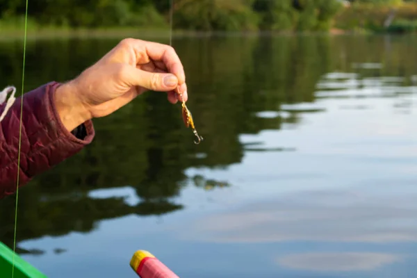 fishing lure held in hand, spinner with a triple hook, a fishing lure is a type of artificial fishing bait used to attract fish.