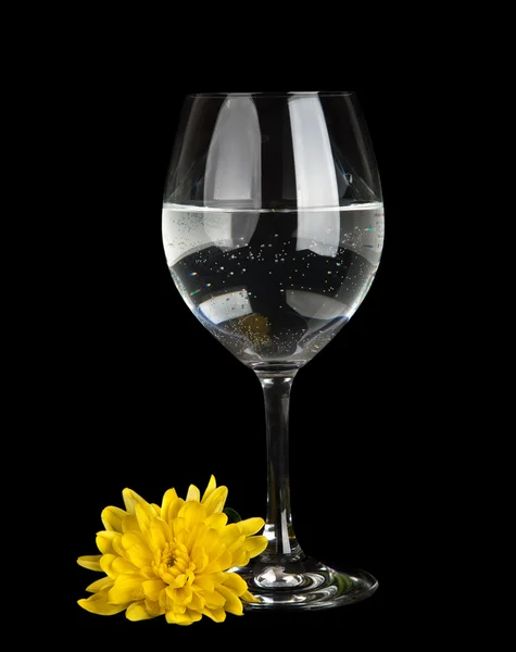 Ποτήρι με νερό και το λουλούδι που απομονώνονται σε μαύρο φόντο — Φωτογραφία Αρχείου