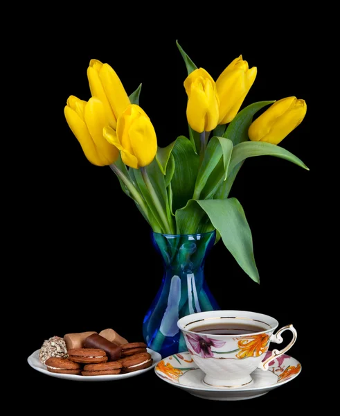Ramo de tulipanes amarillos en jarrón de vidrio y taza de té antiguo llena — Foto de Stock