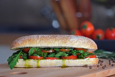 Ciabatta ekmekli lezzetli sandviç, domates, mozzarella, fesleğen, peynir, pesto sosu, taze roka yaprakları. Sağlıklı beslenme. İtalyan mutfağı. Vejetaryen yemek konsepti. Fast food pişiriyorum.