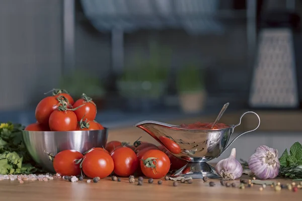 Vegetarian Ketchup in sauceboat on black background, fresh tomatoes, garlic, pepper and spice near. Delicious vegetarian sauce. Cooking marinara from raw cherry tomato. Food backdrop