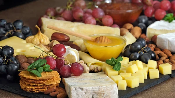 Cheese platter with various types of cheese - parmesan brie roquefort camembert maasdam. Gourmet appetizer, snack food. Assortment of various Spanish french Italian appetizers. Cheese plate 